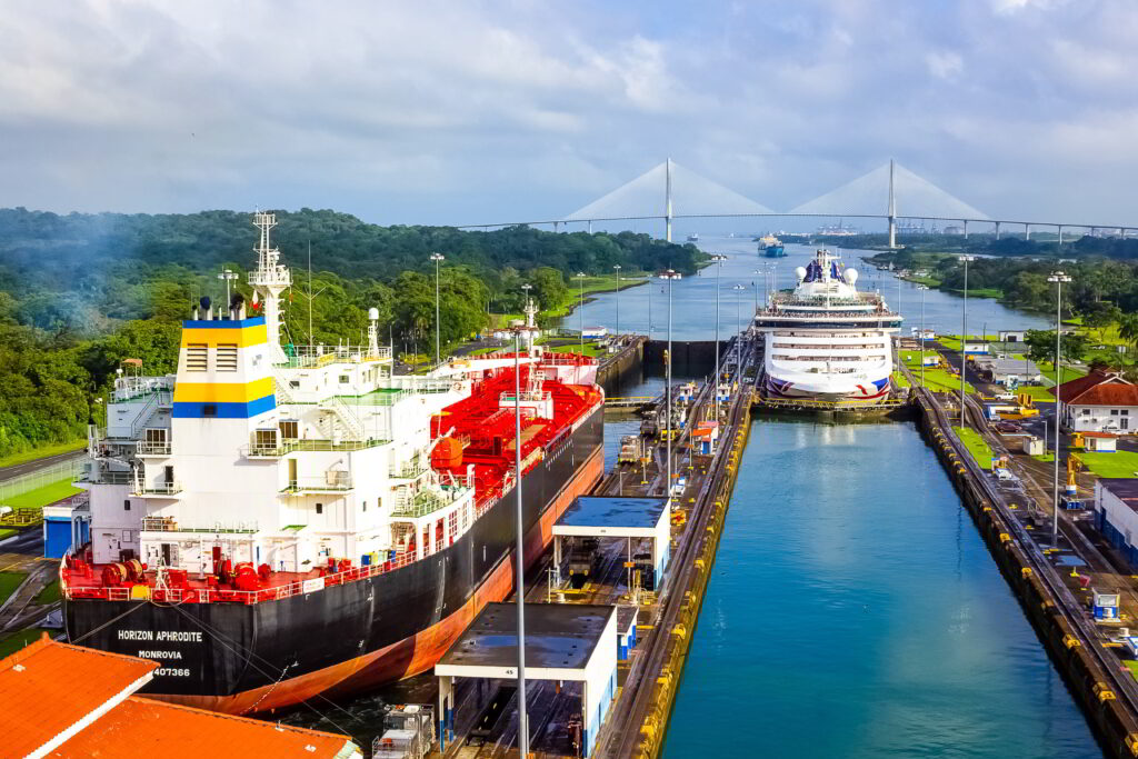 Ships passing through Miraflores lock at the Panama Canal on a sunny day.