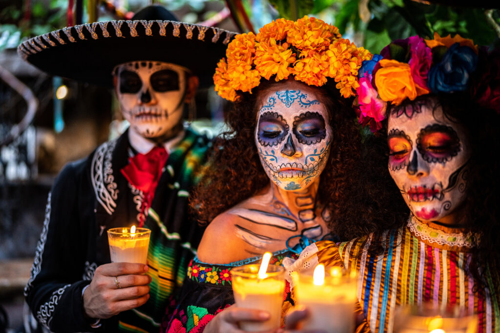 group of people in traditional day of the dead costumes light candels
