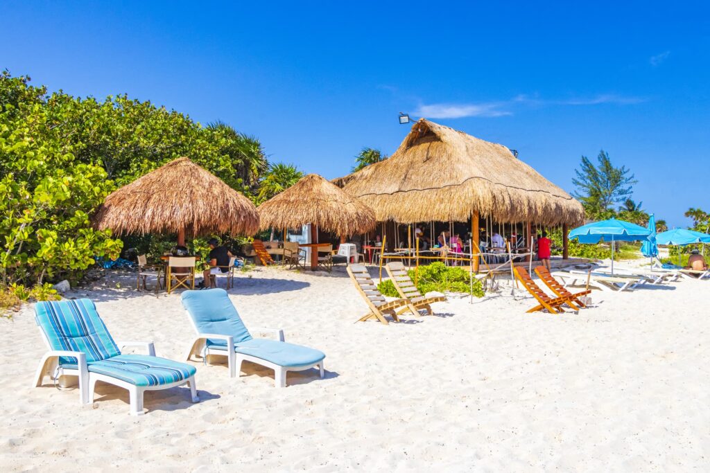 traditional style beach hut and sun loungers on white-sand beach at Playa del Carmen, Mexico.