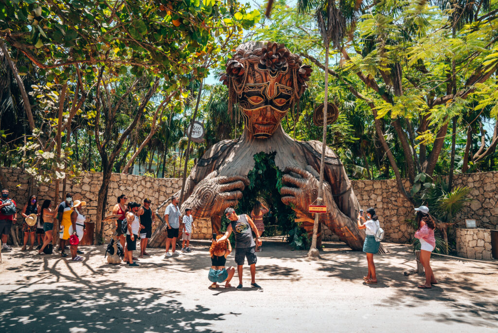 Sculpture in Tulum with tourists in front of it.